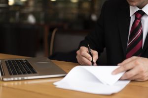 homem-no-escritorio-escrevendo-no-papel